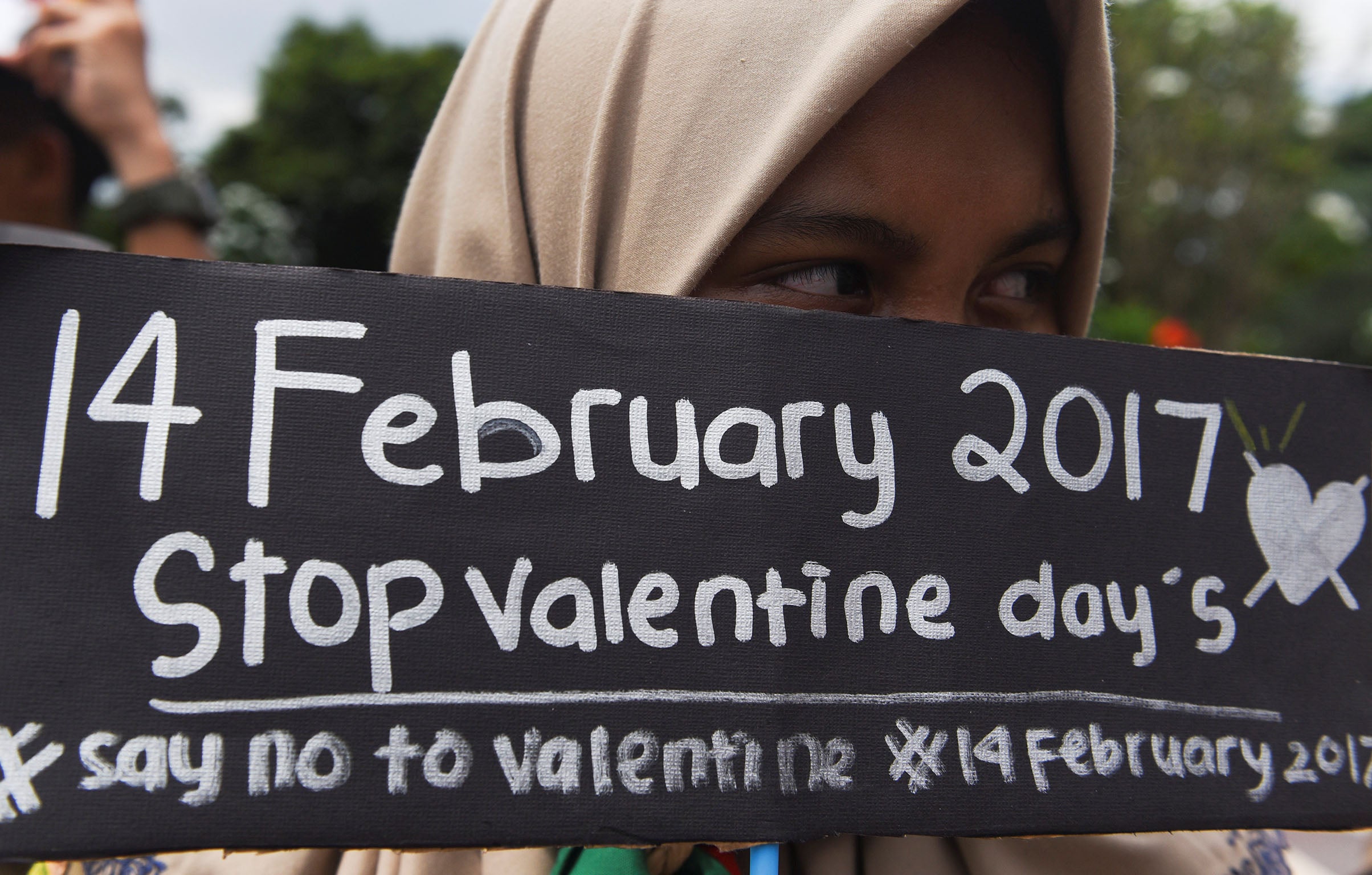 A Muslim student holds a poster during a protest against Valentine's Day celebrations in Surabaya, Indonesia