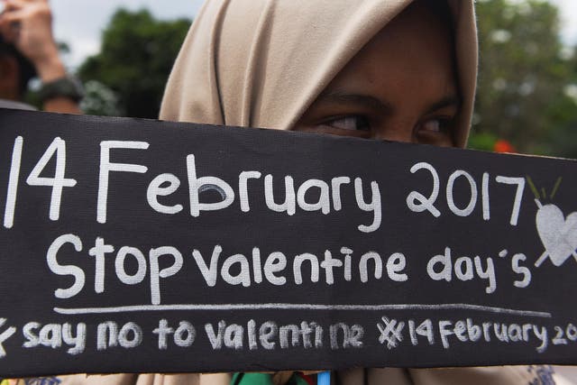 A Muslim student holds a poster during a protest against Valentine's Day celebrations in Surabaya, Indonesia