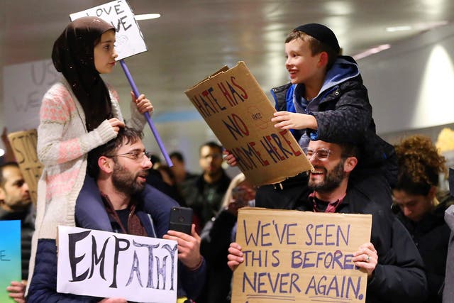 Yildirim, 7, left, sits on her father, Fatih, of Schaumburg, and Adin Bendat-Appell, 9, right, sits on his father, Rabbi Jordan Bendat-Appell, of Deerfield, during a protest at O'Hare International Airport in Chicago