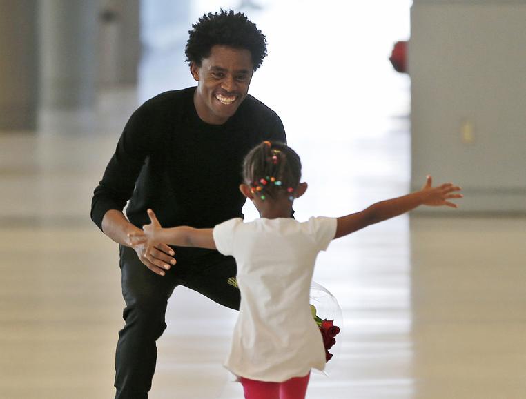 Olympic silver medalist Feyisa Lilesa crouches to hug his daughter Soko, 5, while picking up his family at Miami International Airport
