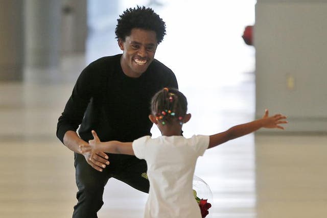 Olympic silver medalist Feyisa Lilesa crouches to hug his daughter Soko, 5, while picking up his family at Miami International Airport
