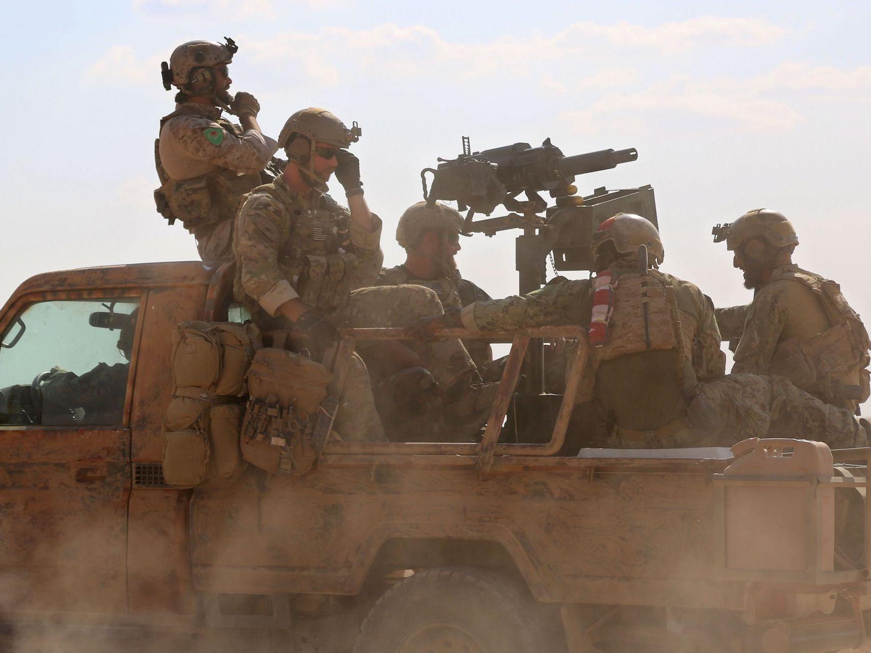 Armed men in uniform identified by Syrian Democratic forces as US special operations forces ride in the back of a pickup truck in the village of Fatisah in the northern Syrian province of Raqa on May 25, 2016.