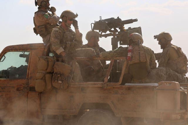 Armed men in uniform identified by Syrian Democratic forces as US special operations forces ride in the back of a pickup truck in the village of Fatisah in the northern Syrian province of Raqa on May 25, 2016.