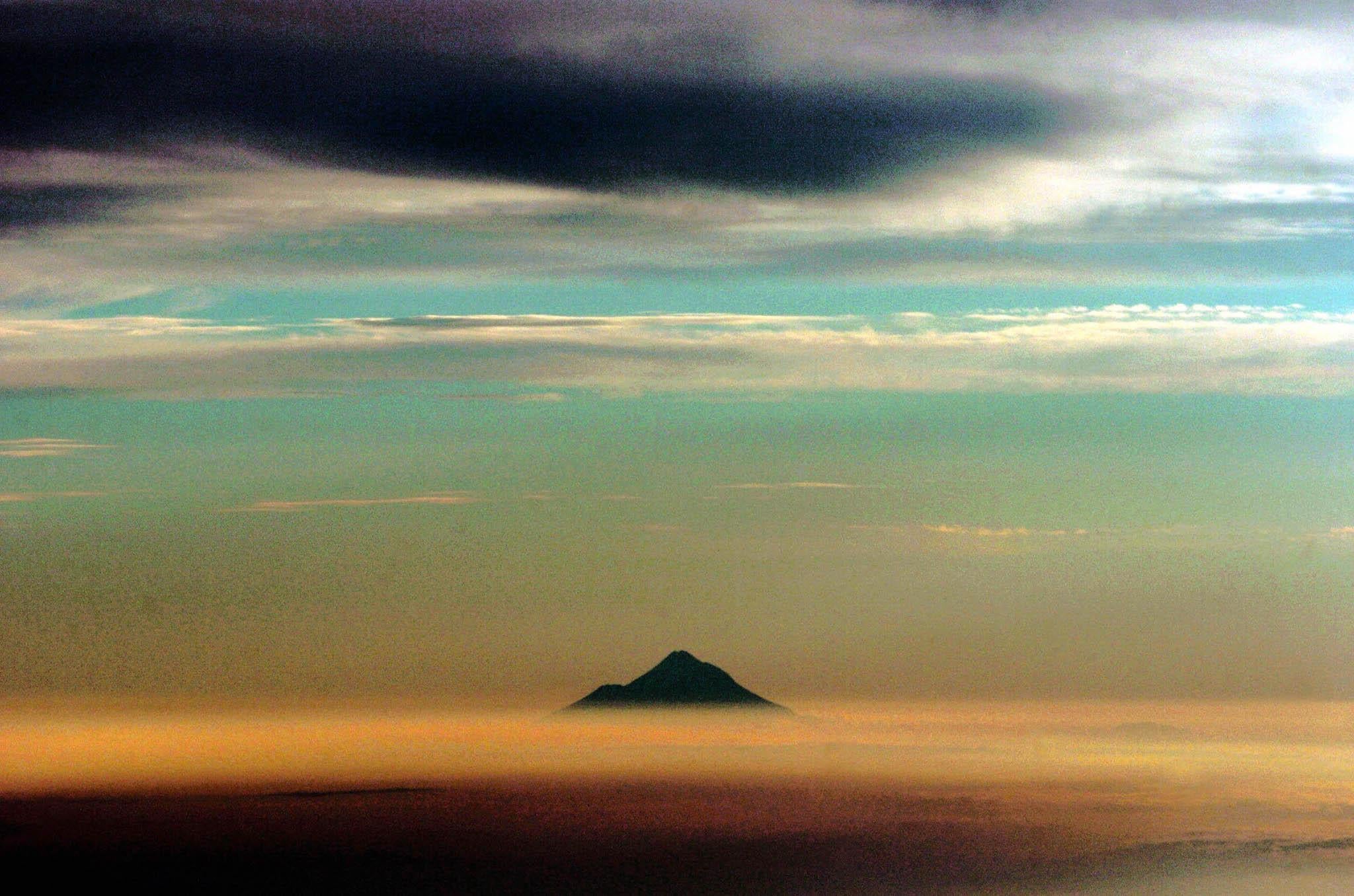 Mt Taranaki pokes its top through a layer of clouds as the sun sets in his photo taken from an airplane in New Zealand, Friday, January 28th, 2005