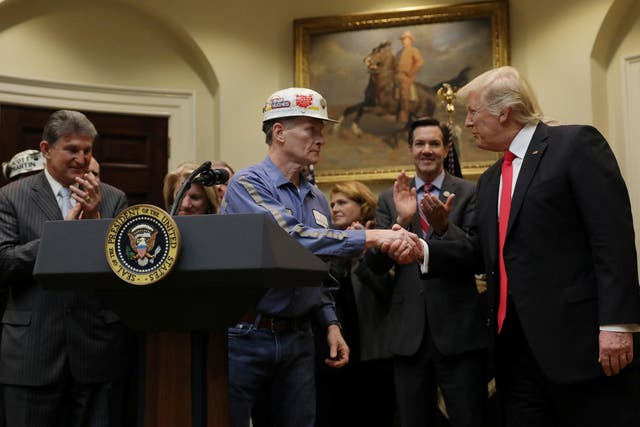 A coal miner shakes hands with US President Donald Trump as he prepares to sign Resolution 38