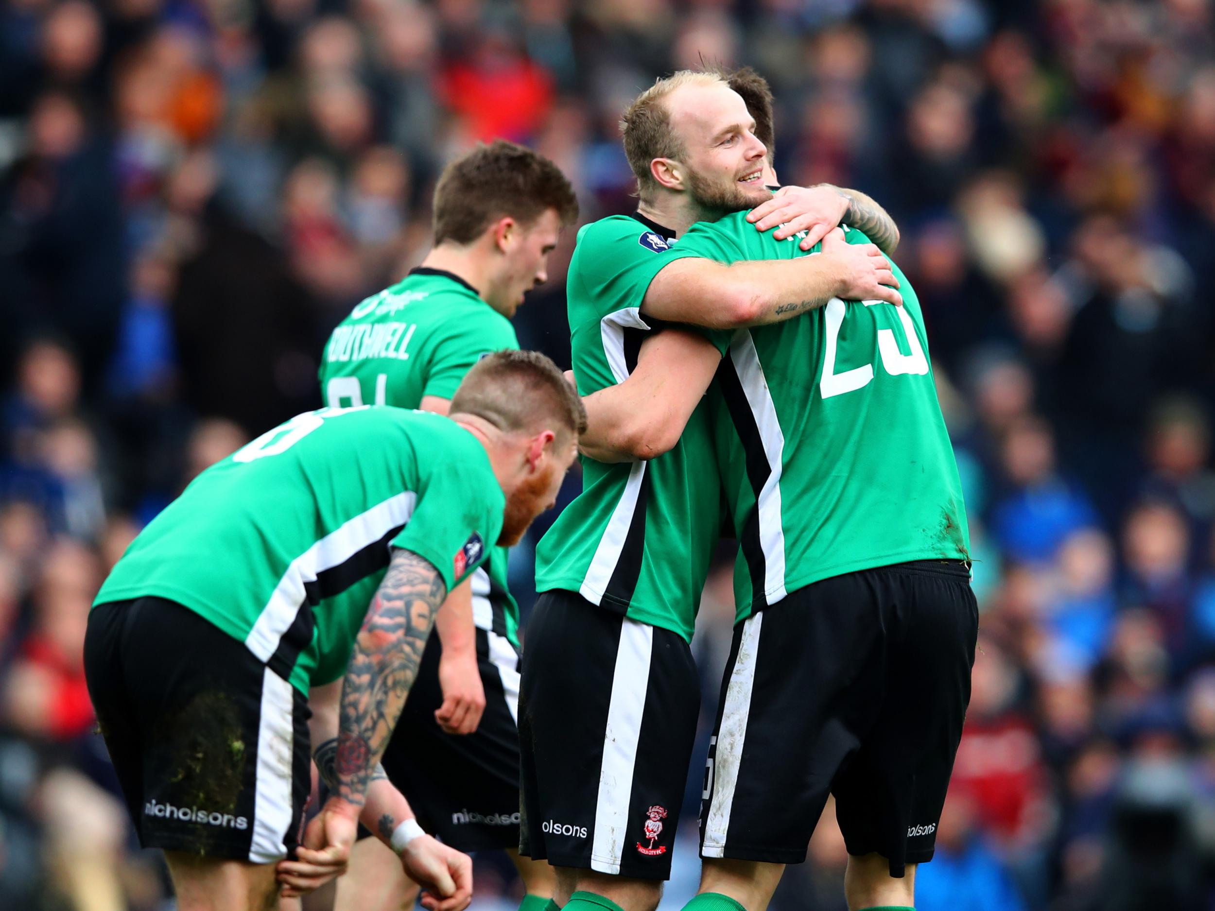 Sean Raggett is mobbed by his team-mates after scoring the winning goal
