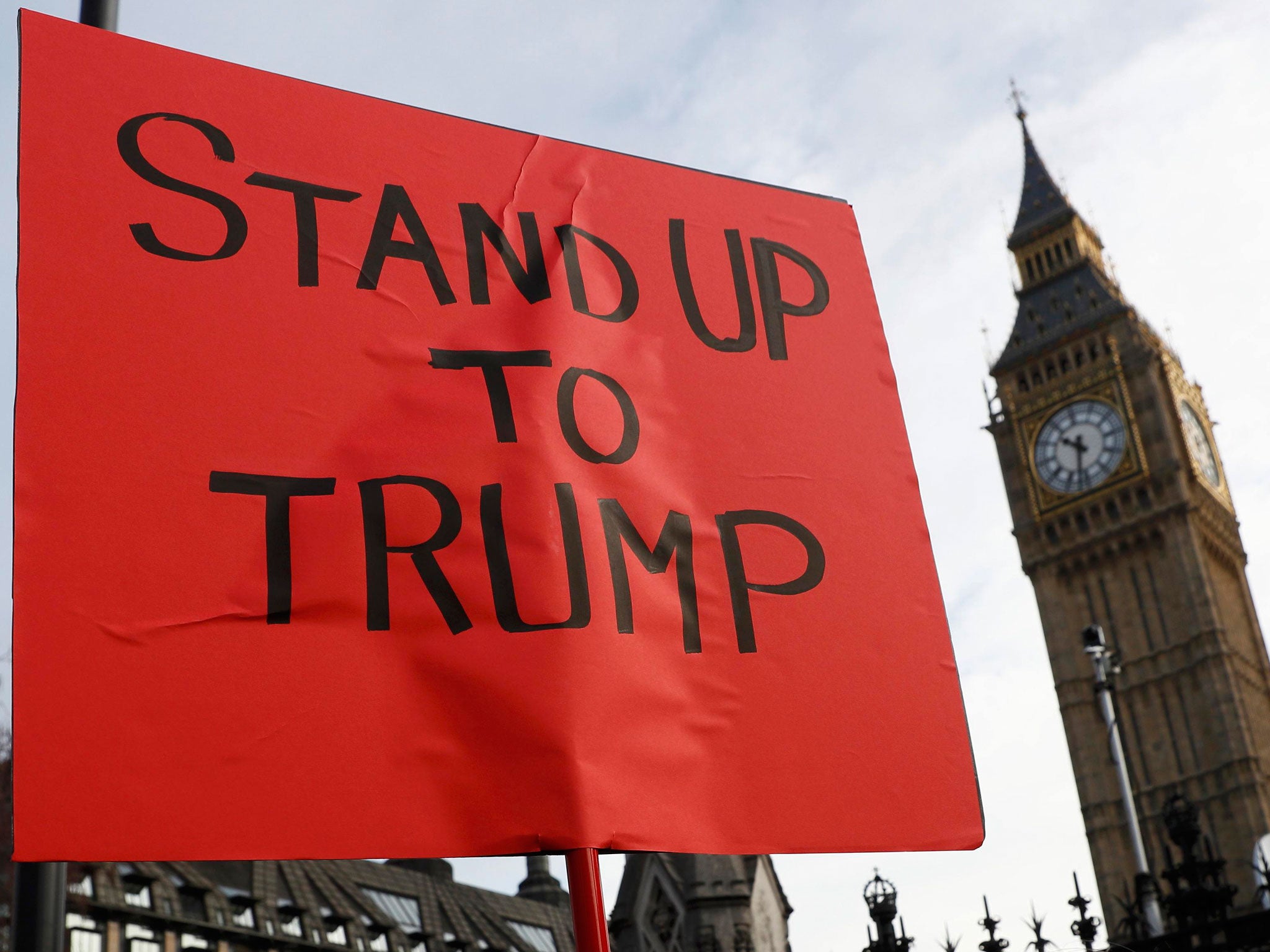 A demonstrator holds a banner that reads "Stand Up To Trump" outside The Houses of Parliament