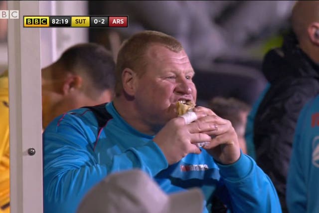 Wayne Shaw tucks into a snack on the sideline during Sutton's FA Cup defeat to Arsenal