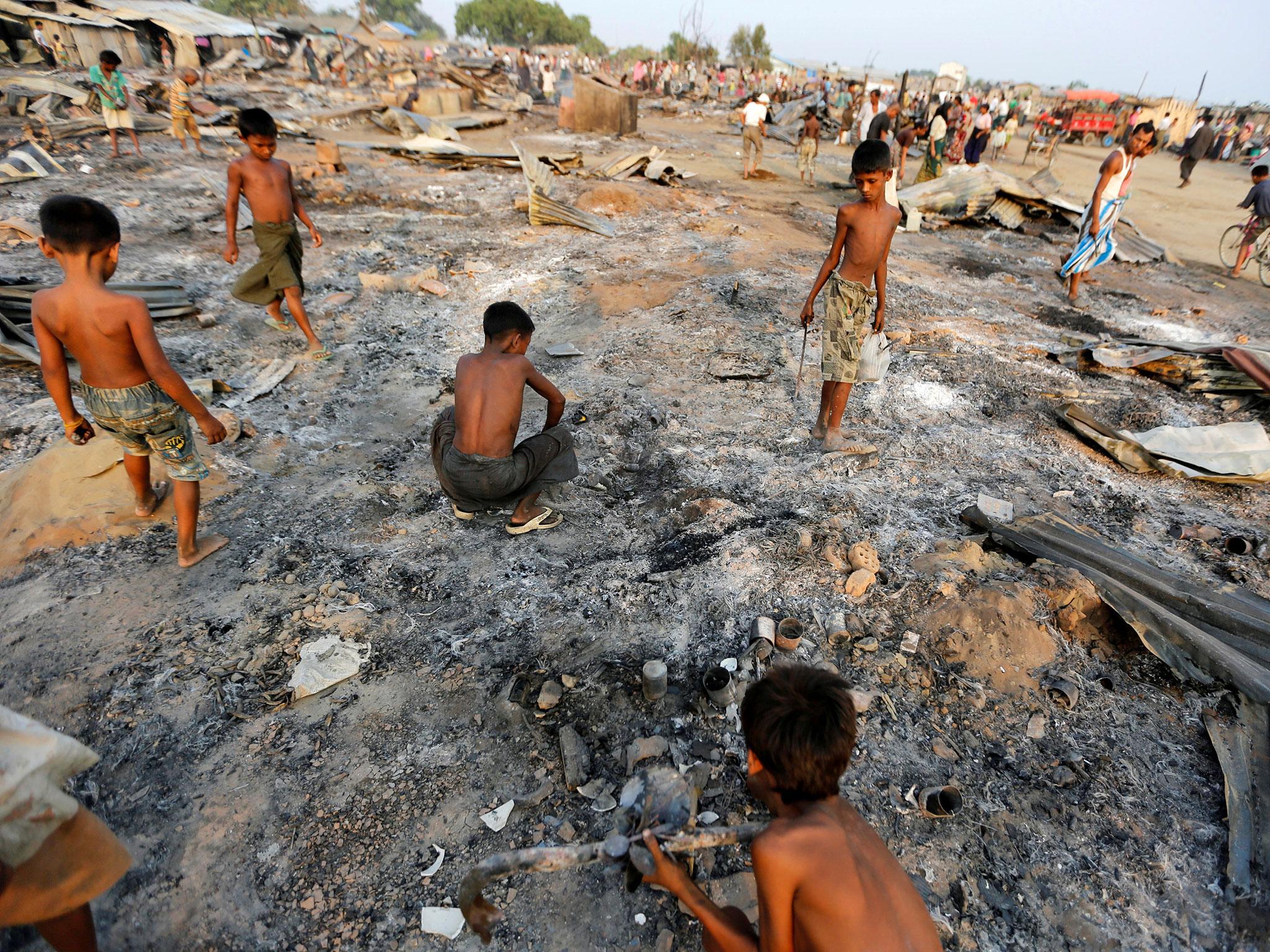 Boys search for useful items among the ashes of burnt houses after fire destroyed shelters at a camp for internally displaced Rohingya Muslims