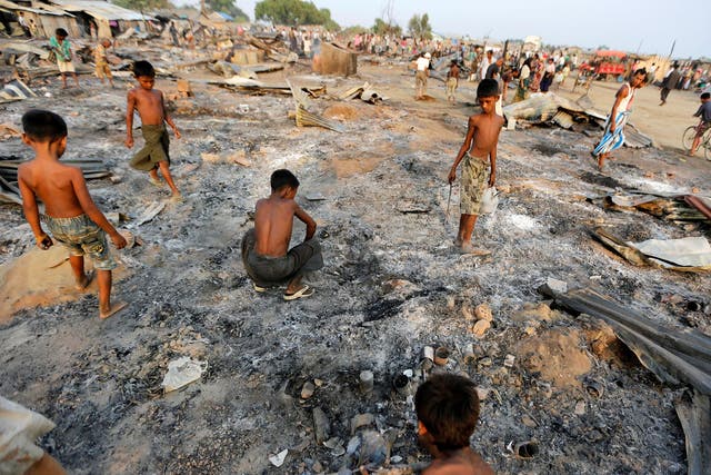 Boys search for useful items among the ashes of burnt houses after fire destroyed shelters at a camp for internally displaced Rohingya Muslims