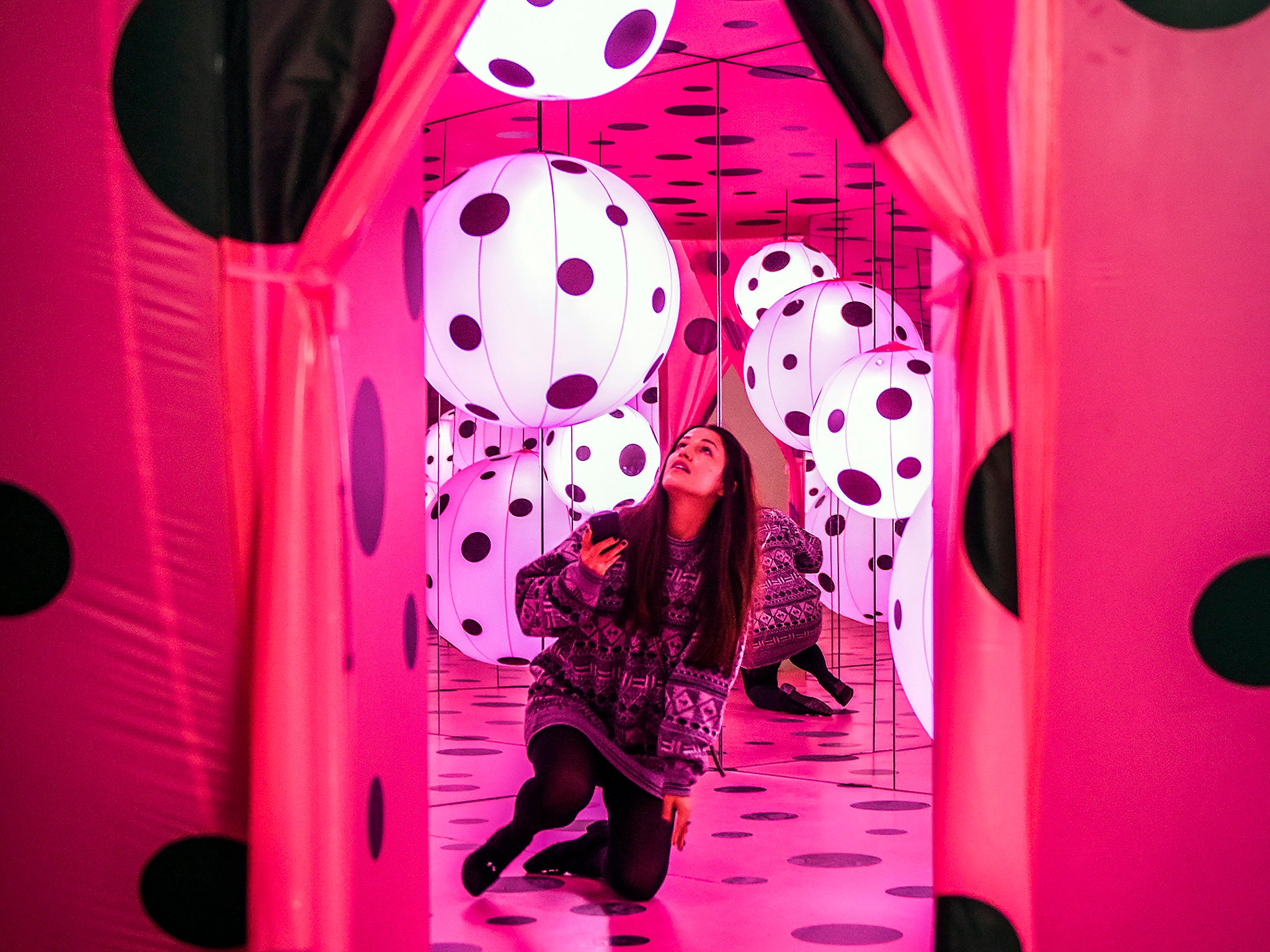 Hirshhorn Museum volunteer Erinda Aliaj takes in ‘Dots Obsession-Love Transformed Into Dots’, part of the exhibition Yayoi Kusama: Infinity Mirrors, a retrospective of Kusama's 65-year career (Bill O’Leary/Washington Post)