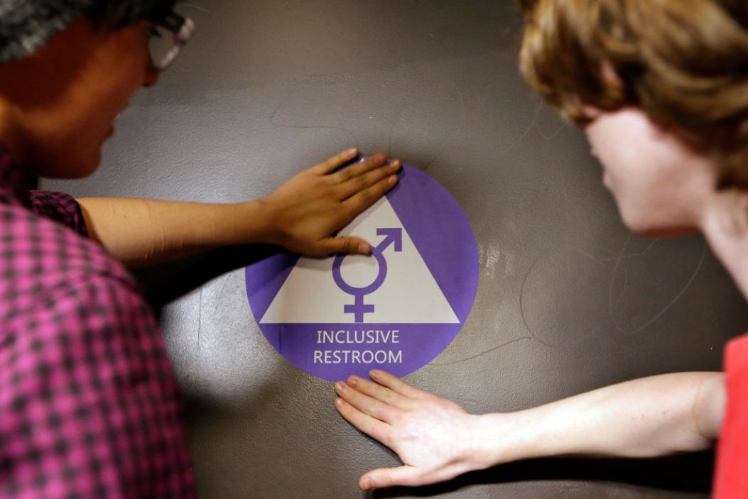Students place a sticker on the door of a gender neutral bathroom at Nathan Hale High School in Seattle on May 17, 2016.