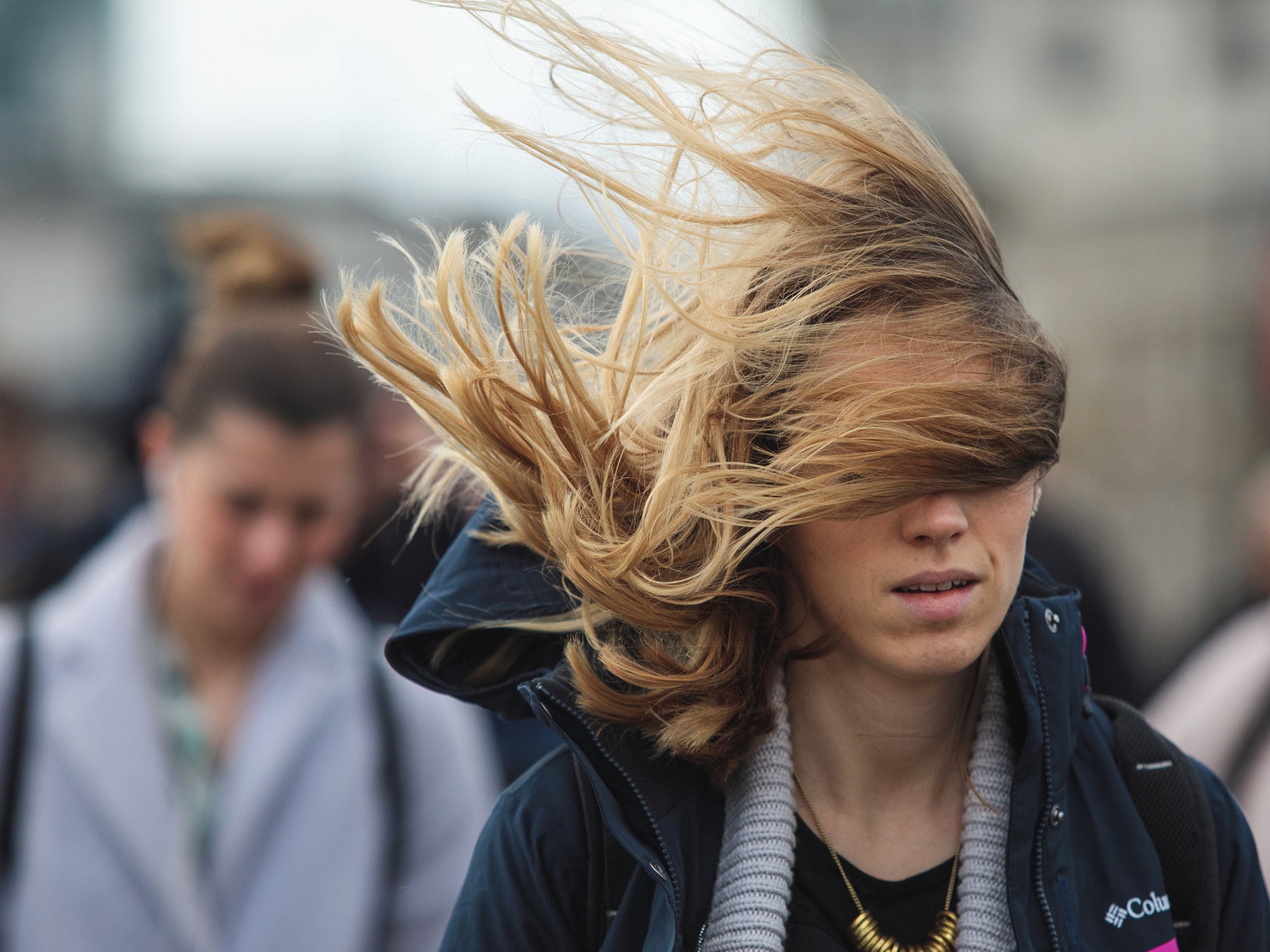 A commuter's hair blows in the wind as they cross London Bridge during Storm Doris