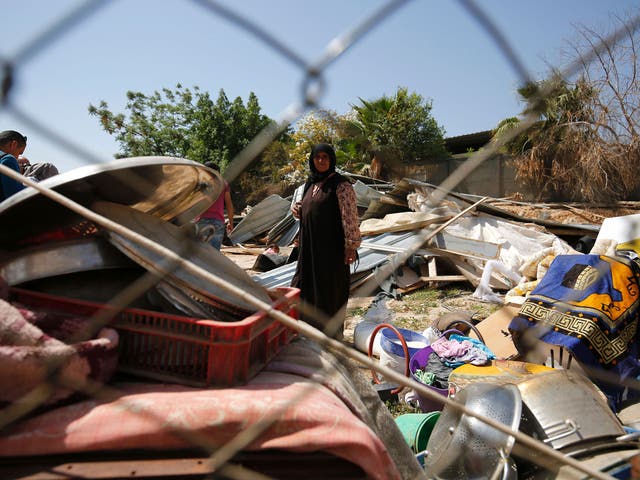 A woman from the Arab Jahalin Bedouin community stands amidst the debris of homes in the West Bank Bedouin camp of al-Khan al-Ahmar on April 7, 2016