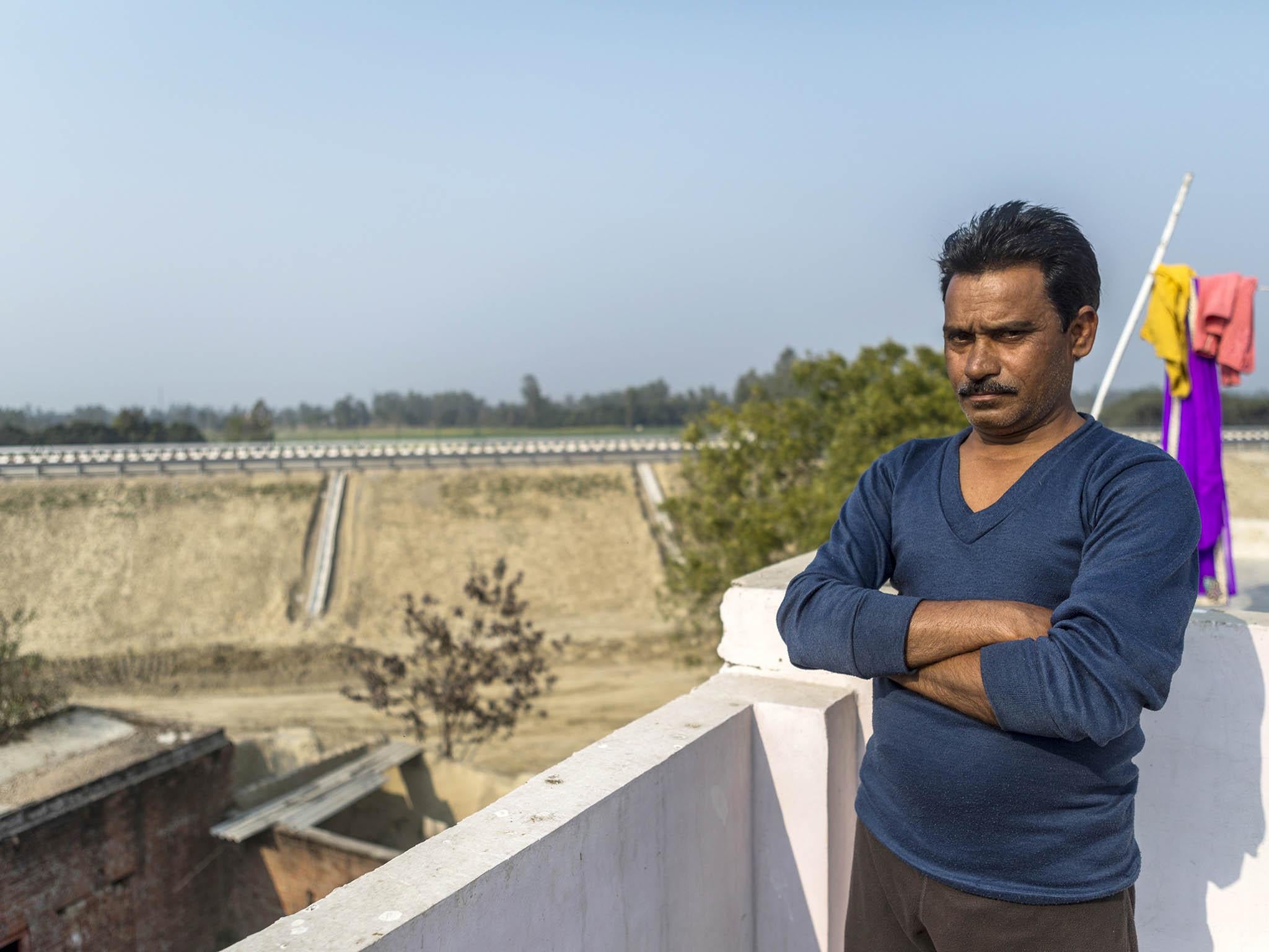 &#13;
Farmer Kailash Singh who sold his land to make way for the construction of the Agra-Lucknow Expressway, in the background, on the outskirts of Lucknow, Uttar Pradesh, India (Bloomberg/Getty)&#13;