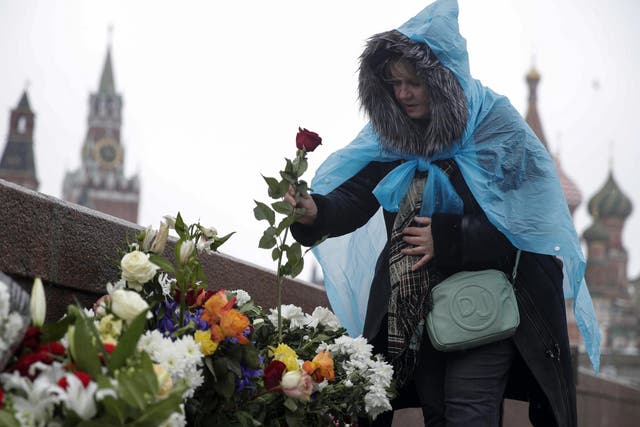 A woman lays flowers at the place where Russian opposition leader Boris Nemtsov was gunned down where he was gunned down two years ago next to the Kremlin Wall in Moscow