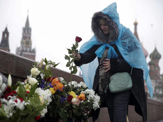 A woman lays flowers at the place where Russian opposition leader Boris Nemtsov was gunned down where he was gunned down two years ago next to the Kremlin Wall in Moscow