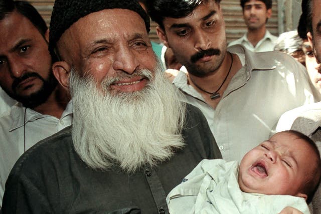 Renowned social worker Abdul Sattar Edhi holds a child handed over to him by local police in Karachi March 15 2002