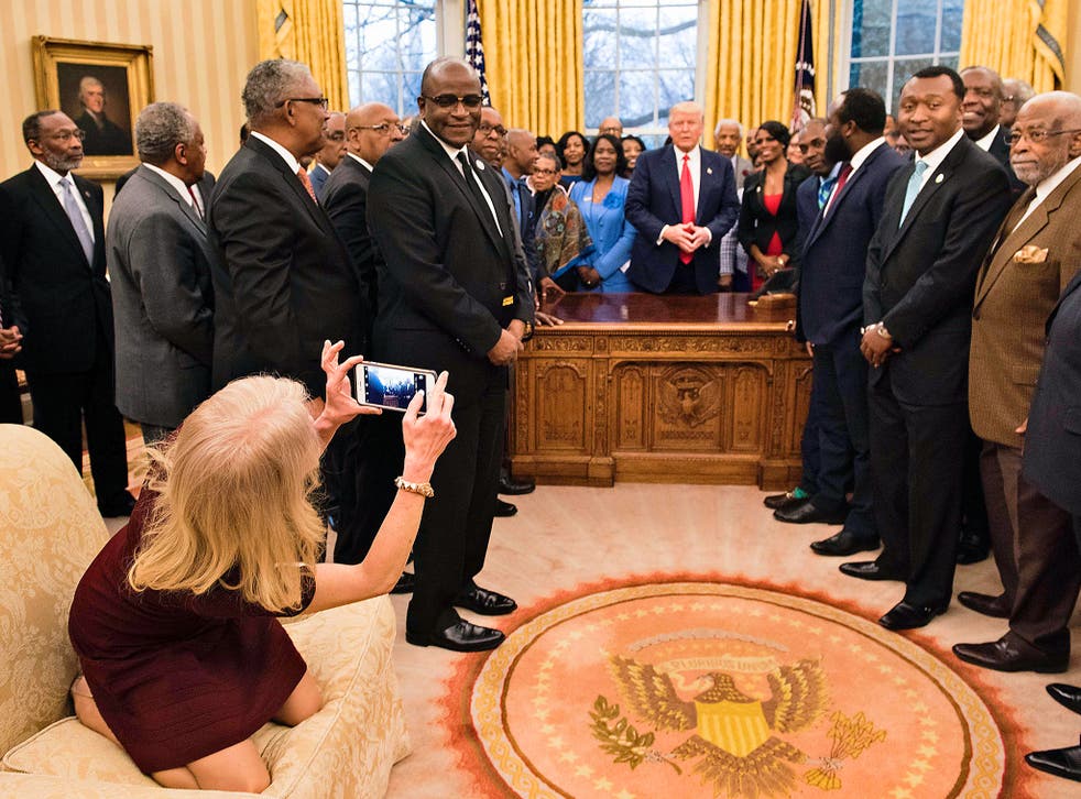 Counselor to the President Kellyanne Conway takes a photo as US President Donald Trump and leaders of historically black universities and colleges talk before a group photo in the Oval Office of the White House