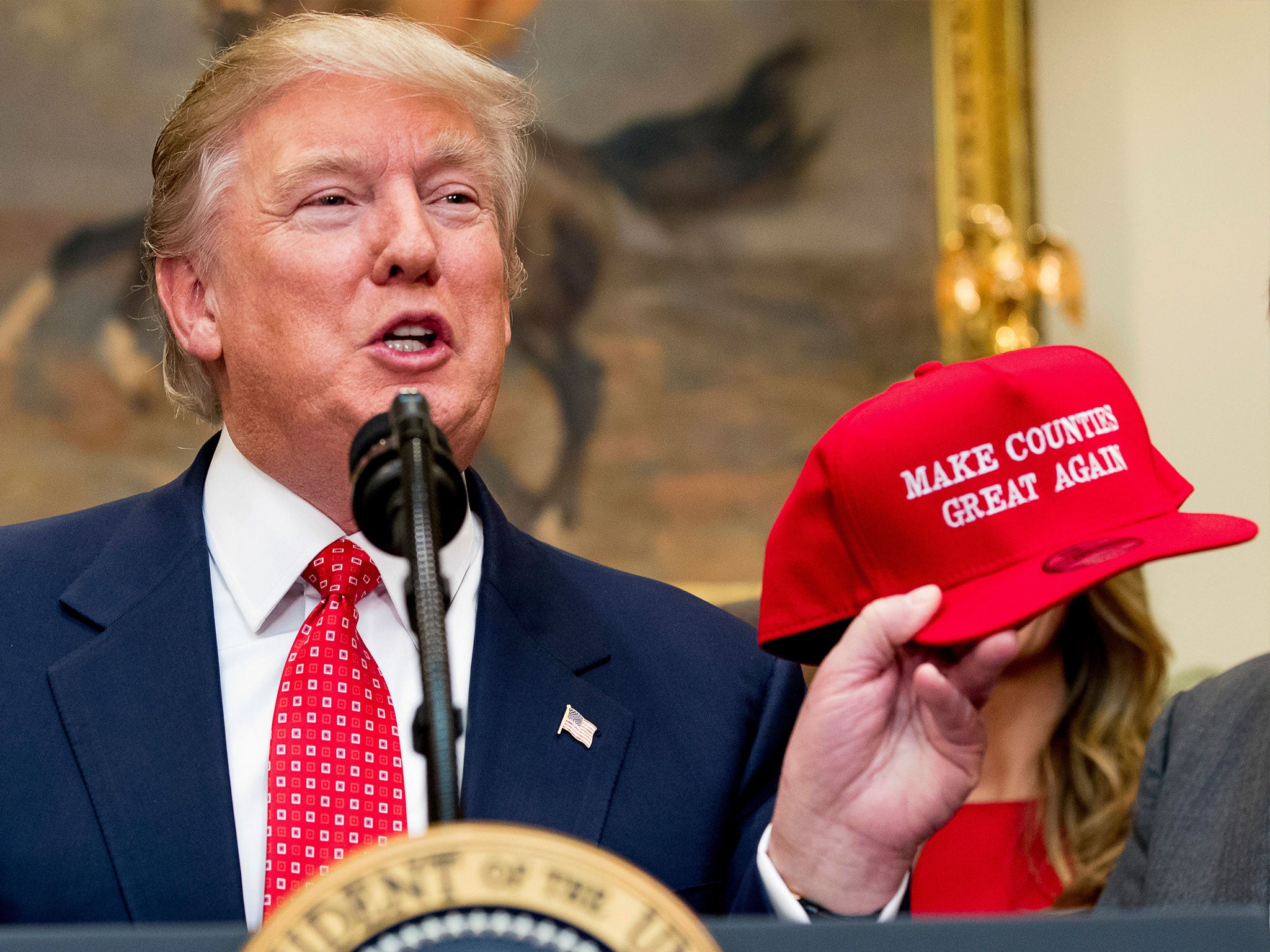 President Donald Trump holds up a hat that reads "Make Counties Great Again"