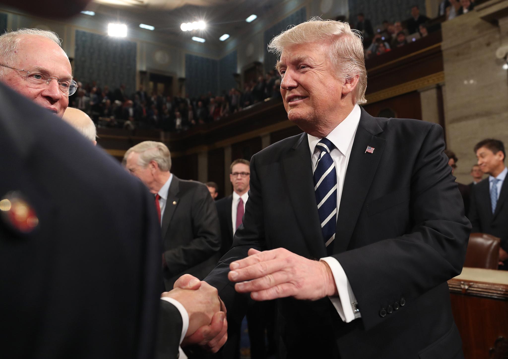US President Donald Trump shakes hands after delivering his first address to a joint session of Congress from the floor of the House of Representatives in Washington