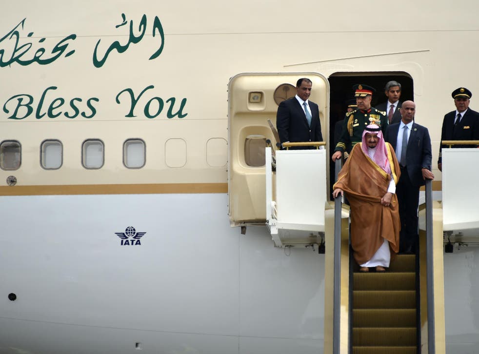 King Salman descends on one of his golden escalators from a plane