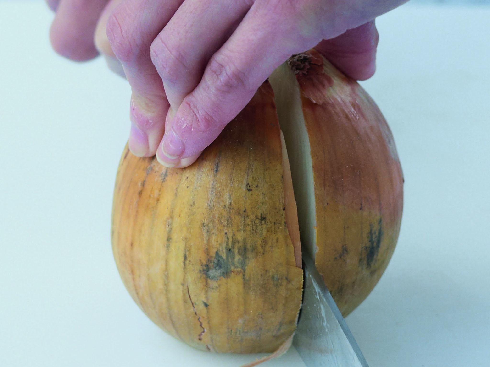 2. Stand the onion with the trimmed top surface down. Using a large, sharp knife (a small knife for shallots), cut down through the onion to halve