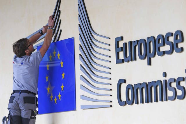 Workers adjust and clean the logo of the European Commission at the entrance to its headquarters