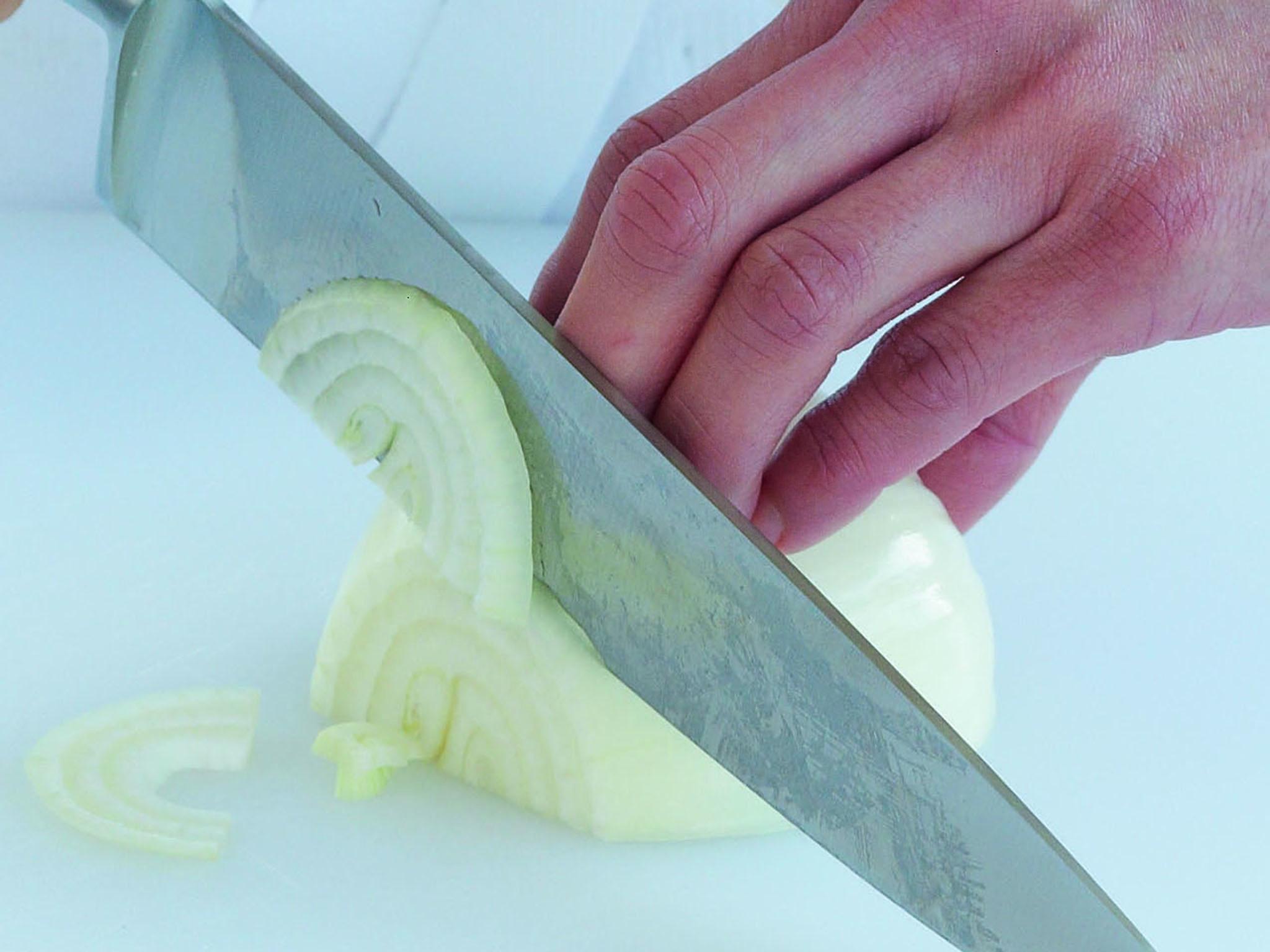 1. Place the onion rounded-side up on the board with the root end furthest from your chopping hand. With your hand in a claw shape and the tips of your fingers bent, hold the onion lightly.Your thumb will support the root end