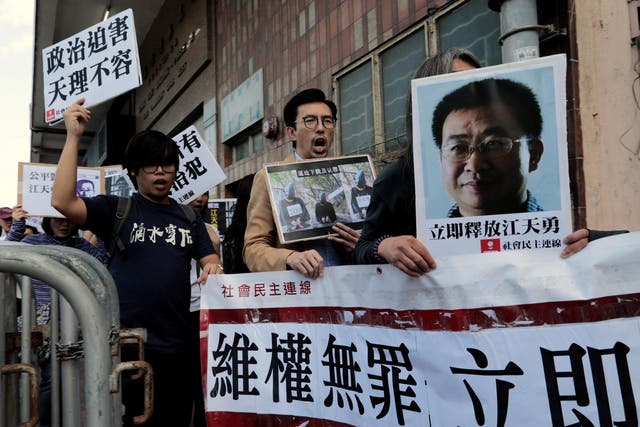 Pro-democracy demonstrators hold up portraits of disbarred lawyer Jiang Tianyong demanding his release outside the Chinese liaison office in Hong Kong