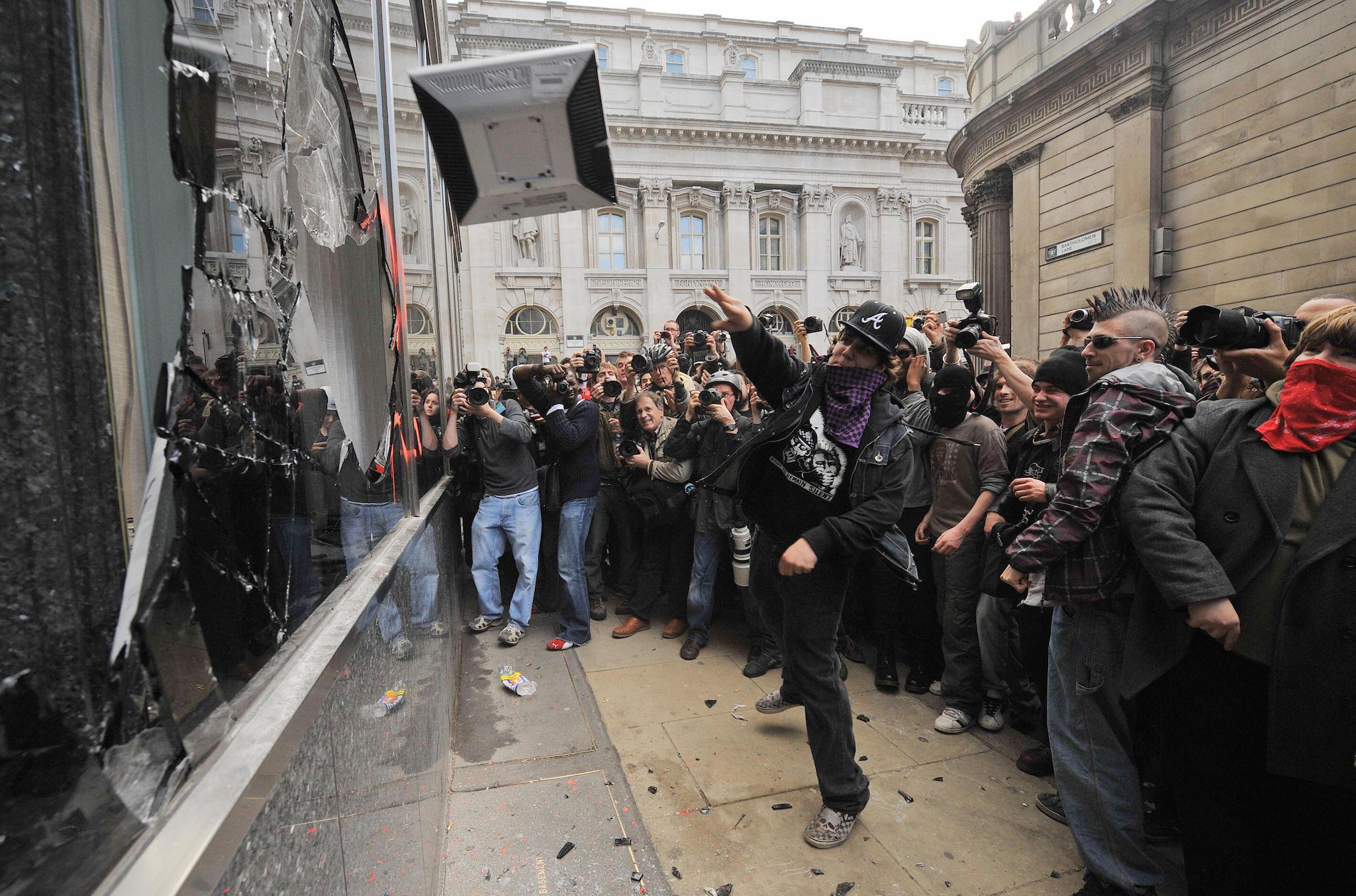 A protestor throws a computer terminal taken from the Royal Bank of Scotland (RBS) office at the smashed windows of a branch of RBS near the Bank of England on April 1, 2009