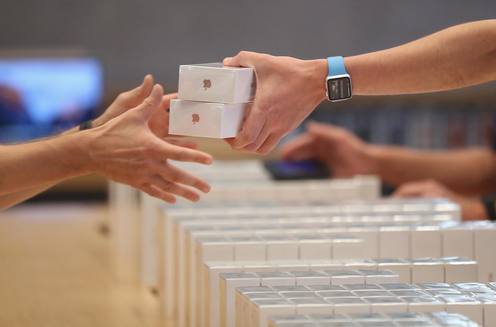 An Apple employee hands over Apple iPhone 7 phones on the first day of sales of the new phone at the Berlin Apple store on September 16, 2016 in Berlin, Germany