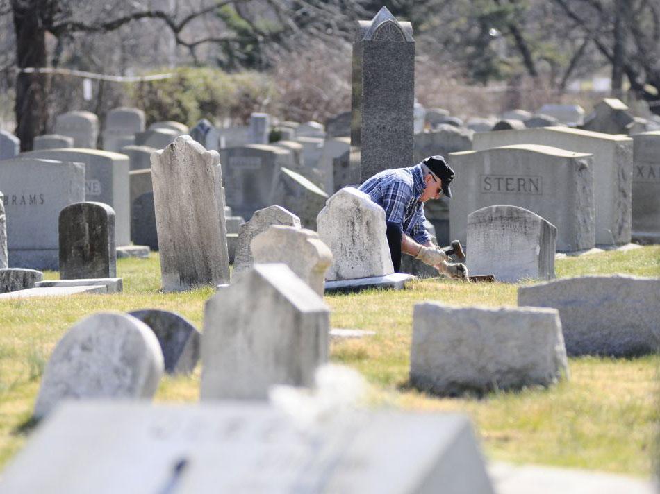 A volunteer helps to restore and repair vandalised headstones at a Jewish cemetery in Philadelphia. Muslims have been offering to stand guard at Jewish sites around the US