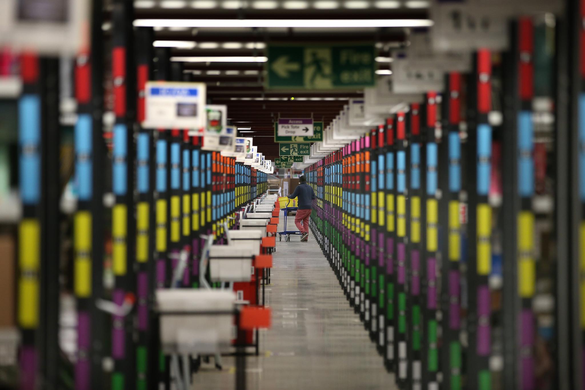 A worker retrieves goods from shelves at Amazon's warehouse on December 5, 2014 in Hemel Hempstead, England