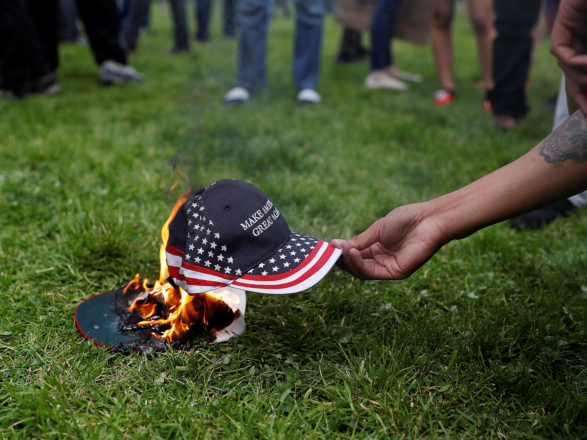 A demonstrator in opposition of US President Donald Trump sets a hat on fire during a 'People 4 Trump' rally in Berkeley, California