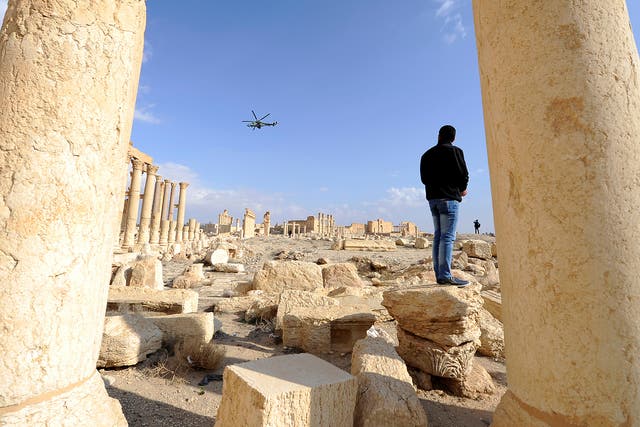 A Russian helicopter flies over ruins in the historic city of Palmyra