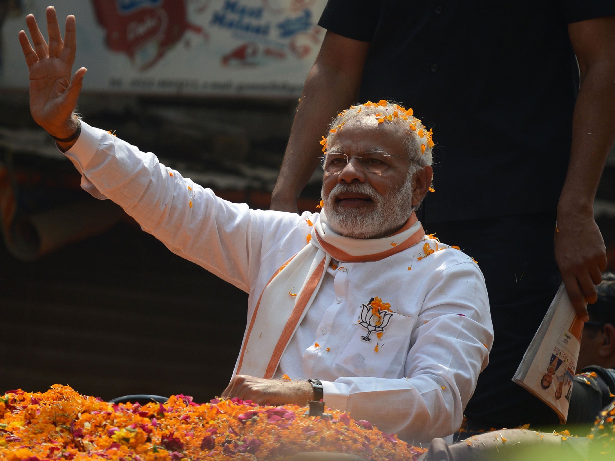 Indian Prime Minister Narendra Modi and Leader of the Bharatiya Janata Party (BJP) waves during a roadshow in support of state assembly election party candidates in Varanasi