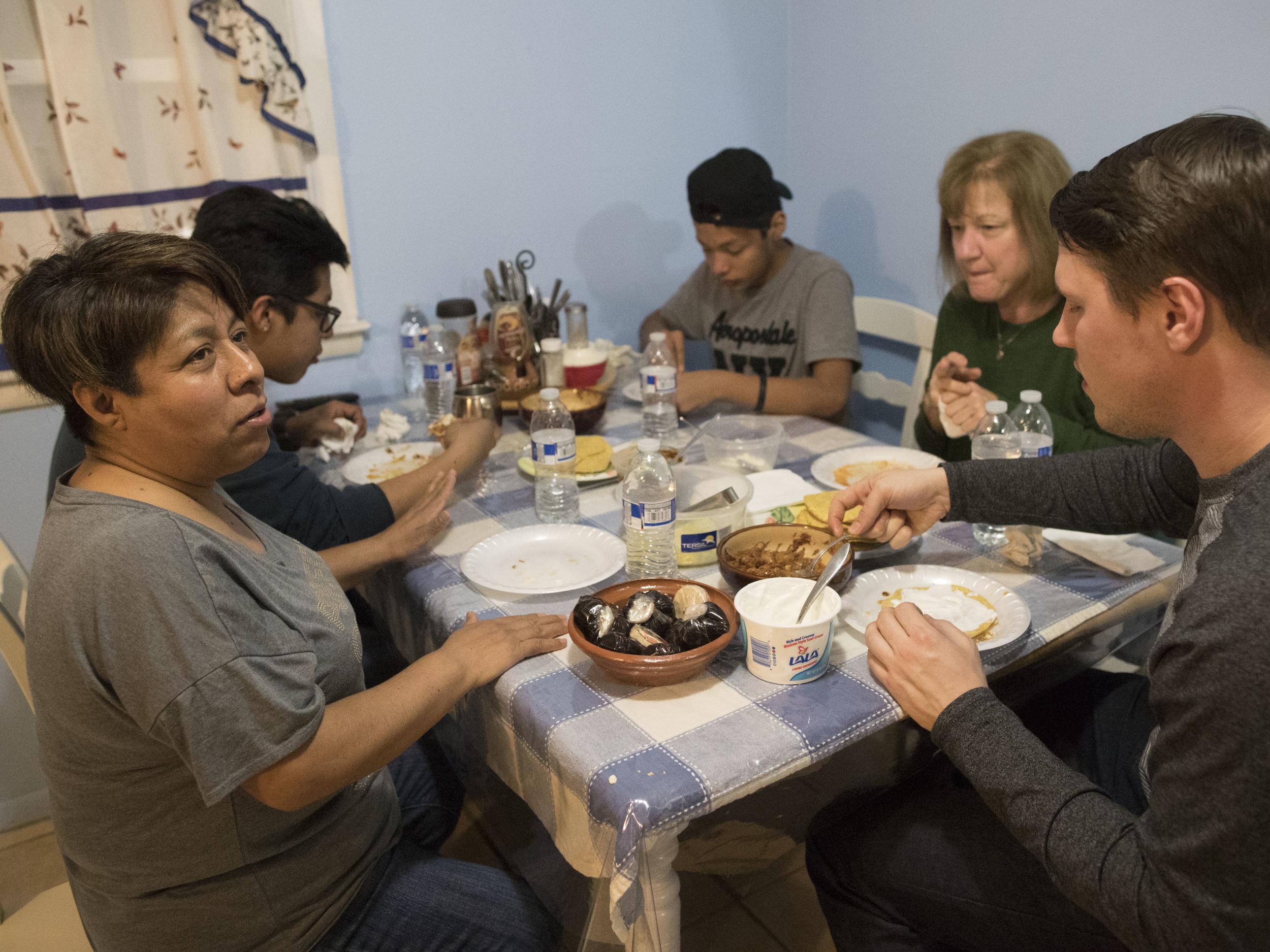 Axel, back left, and Jose Juarez, centre, have dinner with with their mother Maribel Torres, left, and Ruth Silverberg and Silverberg's son Jesse, right, at Maribel's home