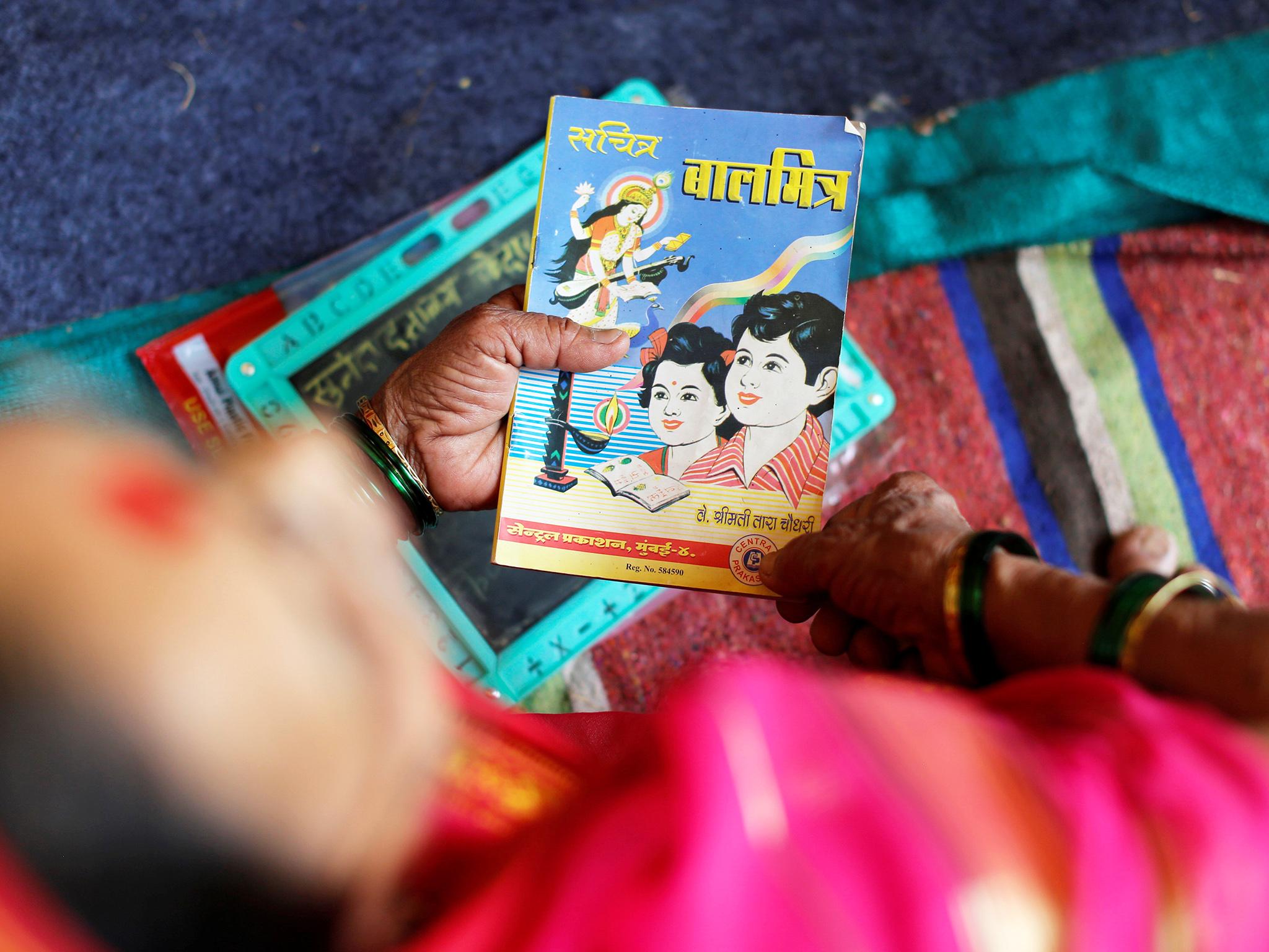 A woman holds a book as she attends a class at Aajibaichi Shaala (Grandmothers' School) in Fangane village, India