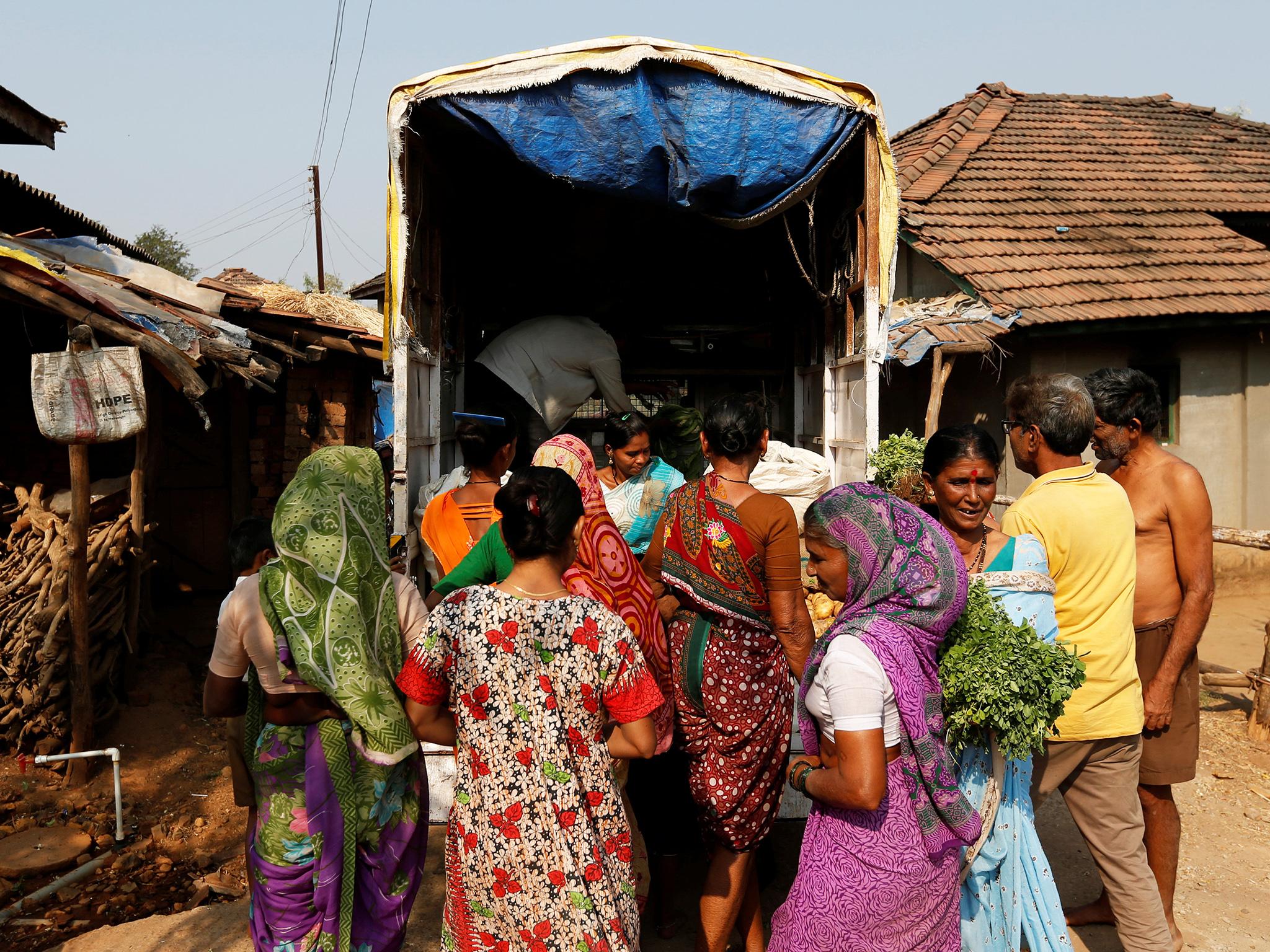 People buy vegetables sold on a truck in Fangane village, India