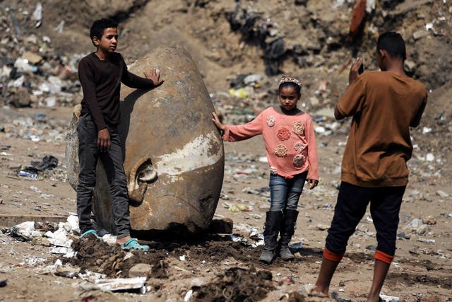 Matariya residents pose for pictures with what appears to be the head of an unearthed statue of Pharaoh Ramses II