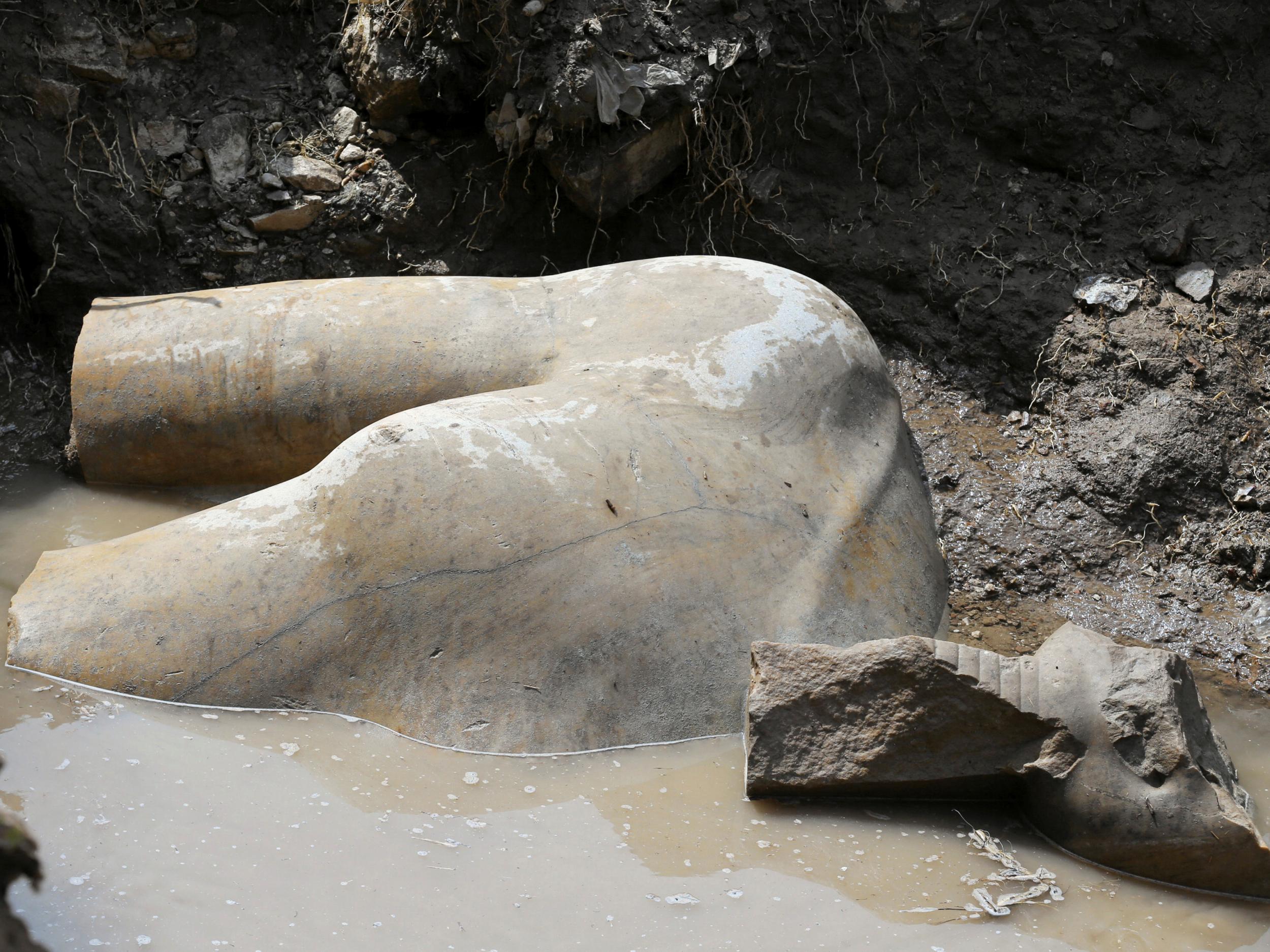 The statue's torso lies in a pool of ground water after being unearthed by a team of Egyptian and German archaeologists