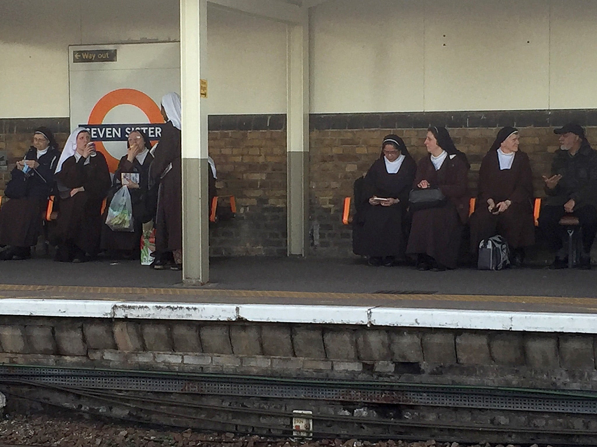 A bemused commuter managed to snap this photo of the seven nuns sitting by the station’s sign