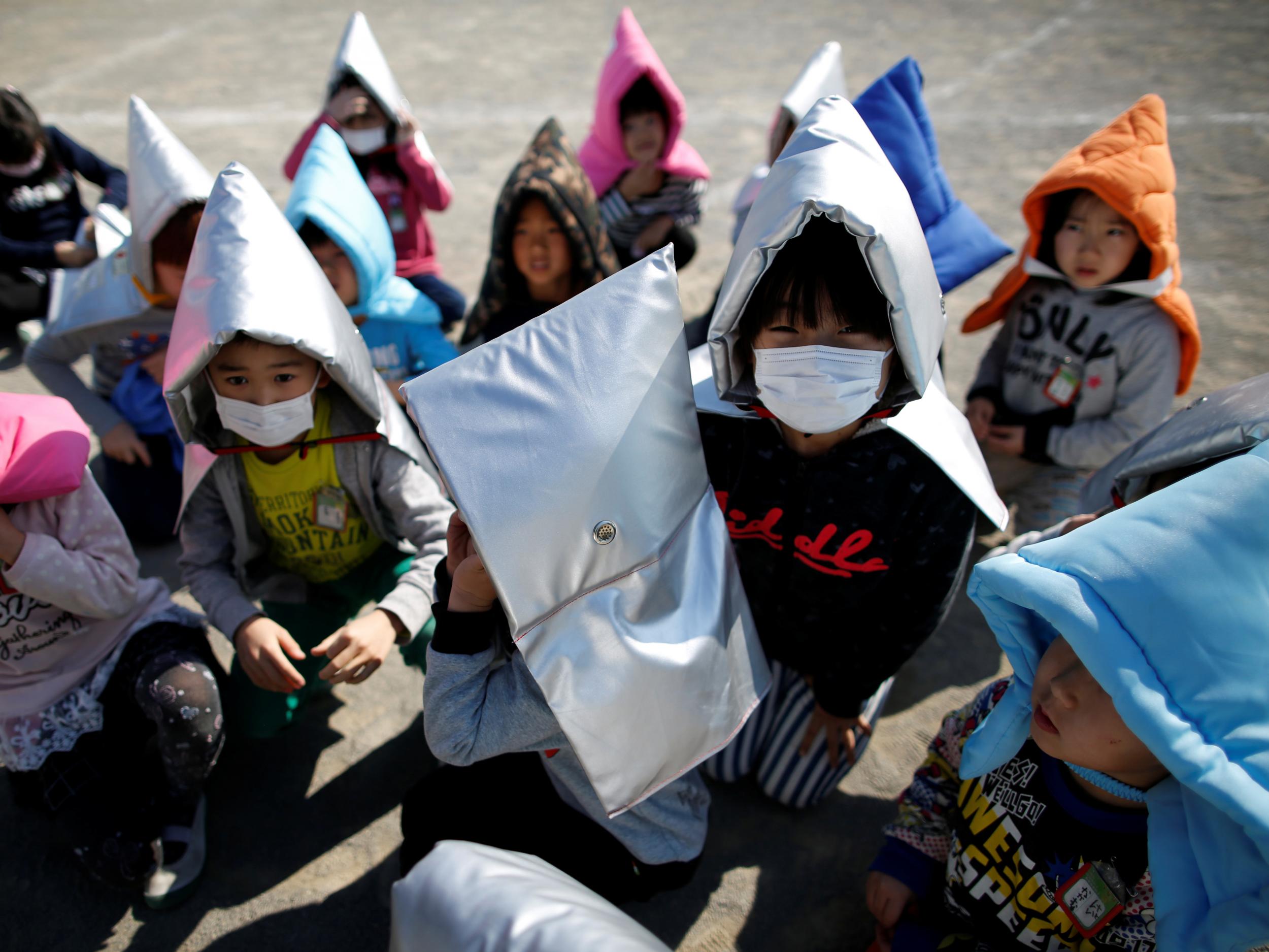 School children wearing padded hoods to protect them from falling debris take part in an earthquake simulation exercise in an annual evacuation drill at an elementary school in Tokyo
