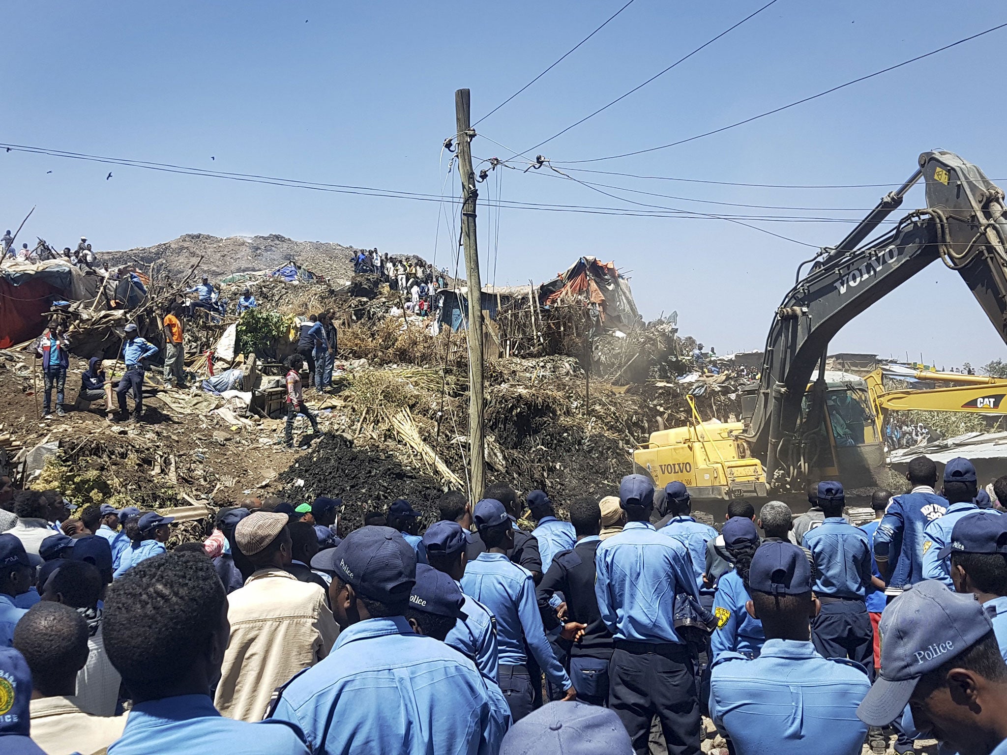 Police officers secure the perimeter at the scene of a garbage landslide, as excavators aid rescue efforts, on the outskirts of the capital Addis Ababa, Ethiopia Sunday, March 12, 2017