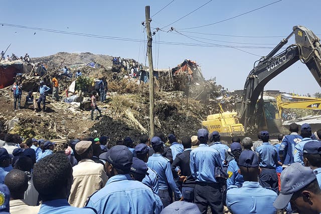 Police officers secure the perimeter at the scene of a garbage landslide, as excavators aid rescue efforts, on the outskirts of the capital Addis Ababa, Ethiopia Sunday, March 12, 2017
