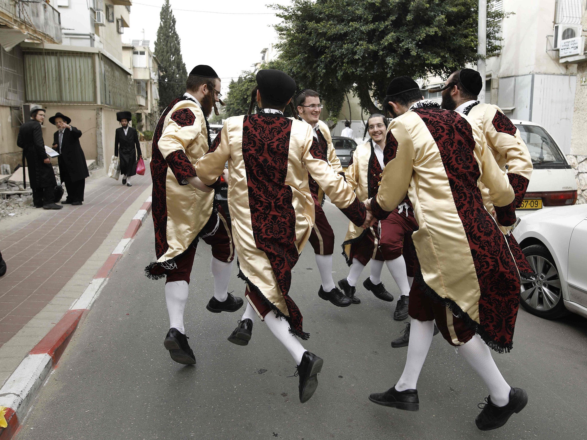 Ultra-Orthodox Jewish men wearing costumes dance on a street in the central Israeli city of Bnei Brak