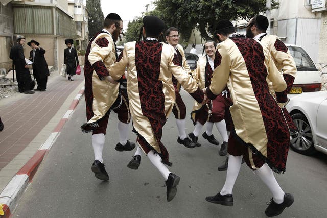 Ultra-Orthodox Jewish men wearing costumes dance on a street in the central Israeli city of Bnei Brak