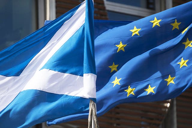 A Scottish Saltire and a European Union flag fly in front of the Scottish Parliament building in Edinburgh