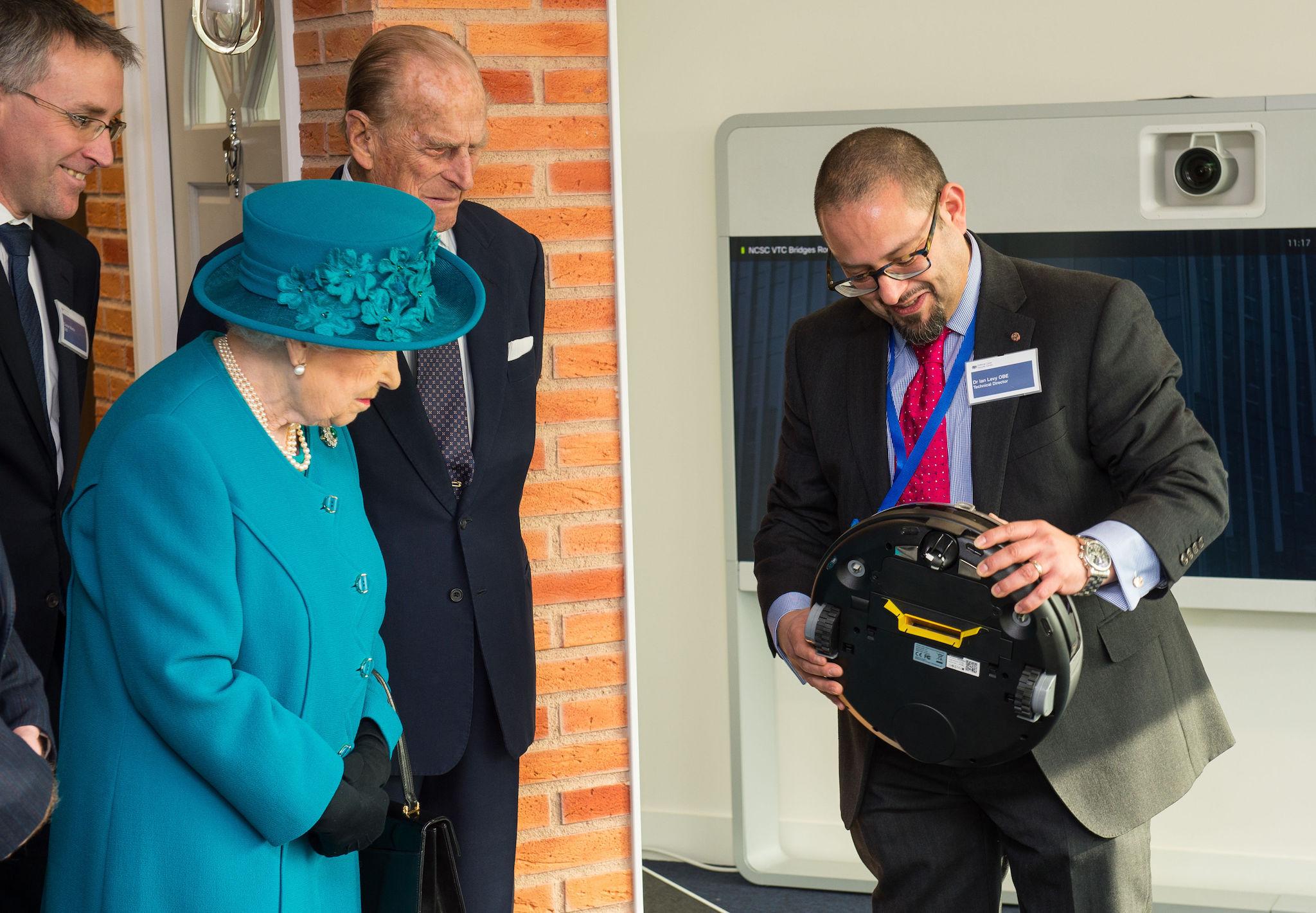 Dr Ian Levy shows the Queen and the Duke of Edinburgh a robot vacuum cleaner which could be vulnerable to cyber attack